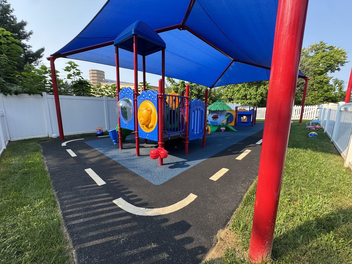 Creative Nursery daycare playground in North Brunswick, NJ, poured-in-place rubber with a road-play design under shade sails